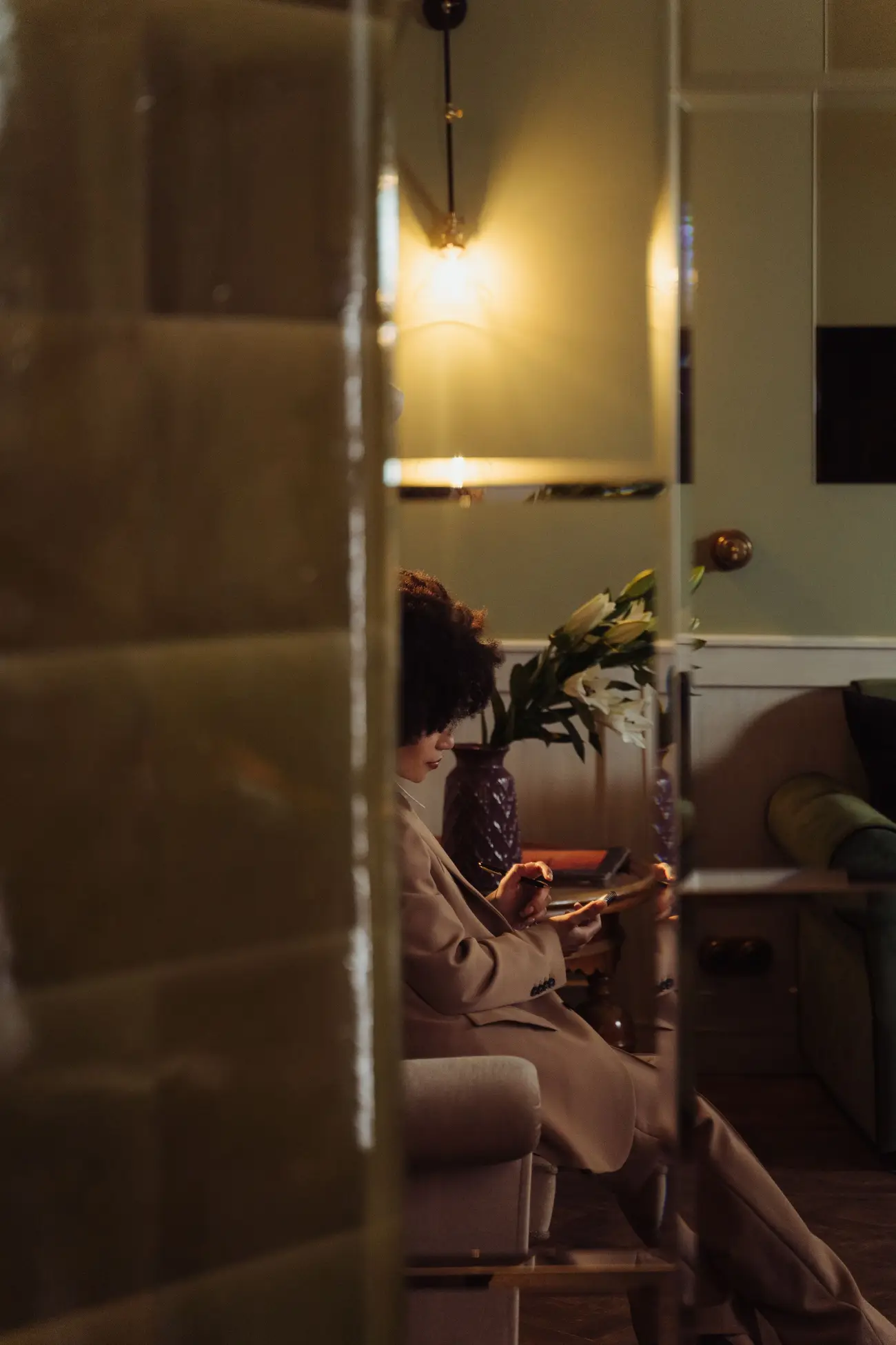 A woman in a lamp-lit living room reading her phone