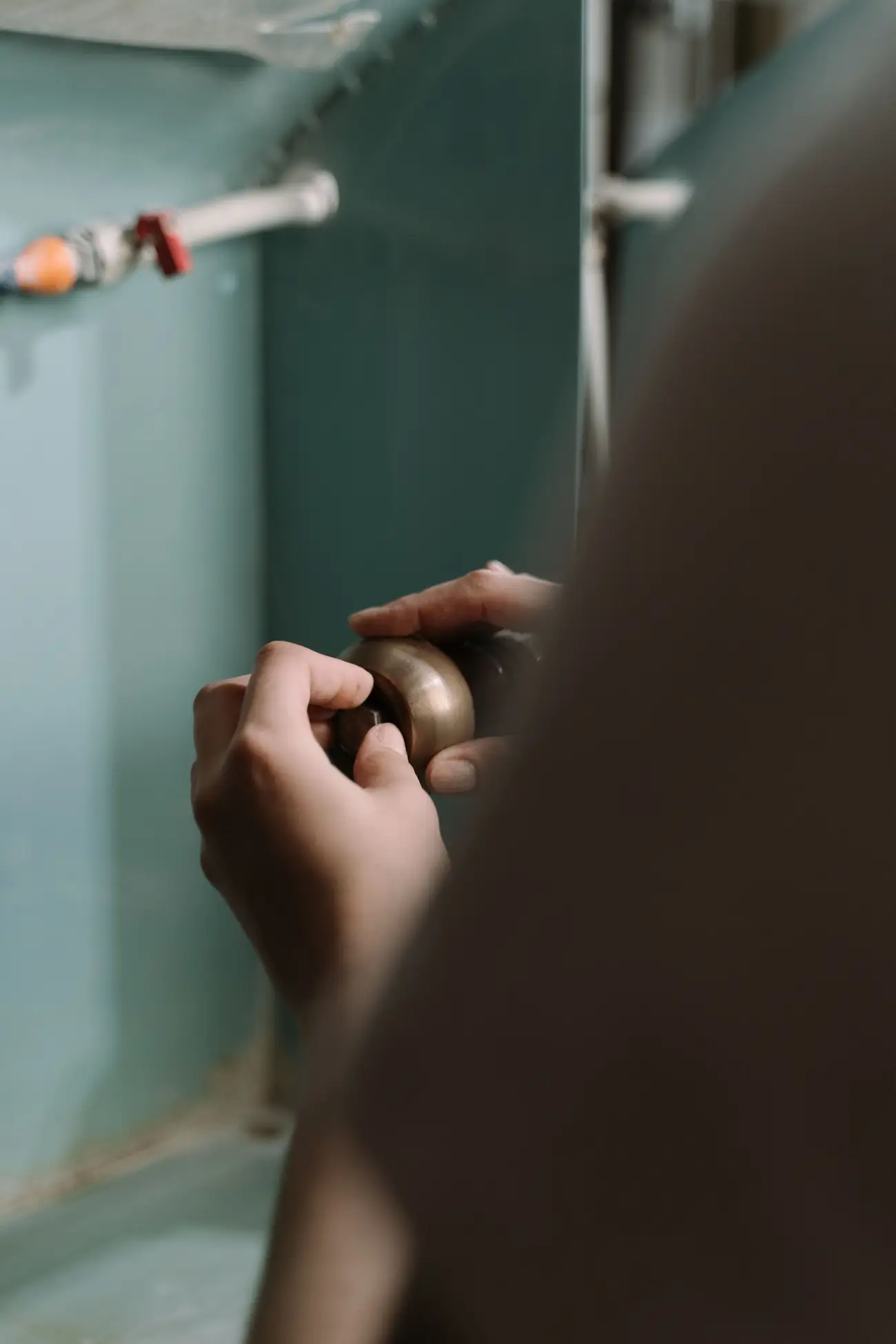 Hands tightening a pipe fitting under a kitchen sink